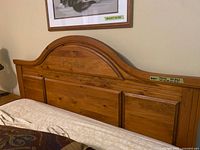 Arched paneled wooden headboard in medium oak finish
