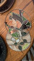 Two stained glass round suncatchers showing floral motifs with metal rings