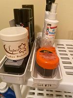 Shelf with leather balsam jar, aerosol cans, protector spray bottle, shine sponge