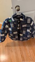 Front view of blue and white patchwork puffer jacket on hanger