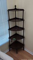 Full view of dark wood corner shelf unit in room corner