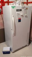 Front and side view of white upright freezer showing handle and overall shape