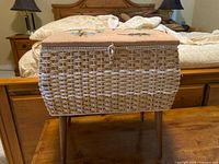 Front view of wicker sewing basket on legs, closed lid, latch visible