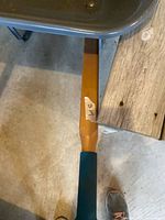 Wooden handle with teal grip attached to wheelbarrow