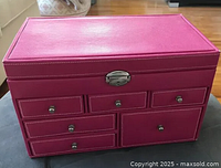 Front view showing pink faux leather jewelry box with six drawers and metal clasp