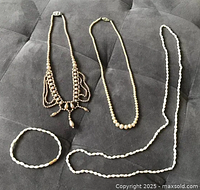 All four jewelry pieces laid out: three necklaces and one bracelet