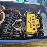 Yellow Union Pacific caboose and bundled black track in tote