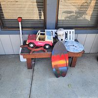 Bench with paddle, toy truck, skimboard, cast iron ship wheel and decorative items