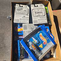 Open box filled with sealed Hot Wheels on blister cards, barcode sides visible