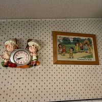 Framed Campbell’s Kids print and ceramic chef clock on wall