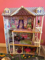 Full front view of three-story dollhouse with roof and furniture in place