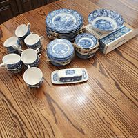 Full lot showing stacks of plates, bowls, cups, butter dish, and boxed plates