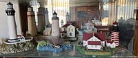 Multiple resin lighthouse replicas displayed in glass cabinet