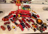 Overall view of McDonald’s diecast cars, haulers, train toys, sign, and burger toy