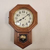 Front view of New England regulator wall clock, oak case, pendulum window