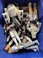 Top-down view of blue bin containing loose Star Wars 12-inch action figures and accessories