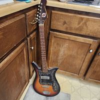Front view showing sunburst body, pickguard, pickup, bridge and missing strings