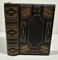 Front cover and spine detail of the 1870 leather bound book The Hand of God in History by Rev. Hollis Read, featuring gold embossed decorative elements and inscriptions.