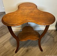 Front view of antique clover-shaped wooden parlour hall table showing top and front legs.