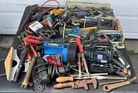 Photo of assorted tools and storage bin showing various hand tools including a spotlight, clamps, pliers, hammers, saws, and other small tools all used and untested.