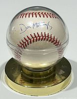 Front view of the autographed baseball in the clear display sphere showing Don Mattingly's signature