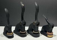 Four vintage cast iron seal press embossers shown side by side showing lever handles and bases.