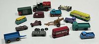 Full lot view showing 16 vintage diecast car models and accessories including multiple trucks, buses, and trailers in various colors.
