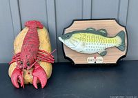 Both Big Mouth Billy Bass mounted fish plaque and Rocky the Singing Lobster wall plaque together side by side.