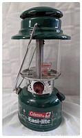 Front view of green Coleman Easi-Lite Model 325 lantern showing the entire lantern with metal top and glass middle section.