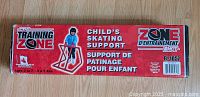 Box packaging of child's skating support showing front label with red background and bilingual text