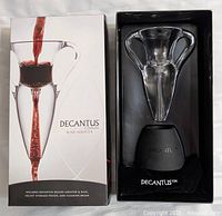Photo showing Decantus Deluxe Wine Aerator in the original box with black base inside, clear glass design with handles.