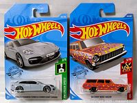 Photo showing both toy cars in original Hot Wheels packaging: silver Porsche Panamera Turbo S E-Hybrid Sport Turismo on left and orange '54 Chevy Nomad Wagon on right