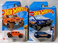 Two Hot Wheels diecast toy cars in original packaging, showing front and side of cars with blue backer card and Hot Wheels logo.