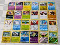 Image showing 24 assorted Pokémon cards laid out flat, including some foil cards.