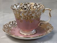 Front and side view photo showing the tea cup and saucer with gold and pink floral design.