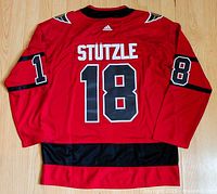 Back view of the red hockey jersey showing 'STUTZLE' and the number 18 on back and sleeves
