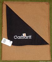 Folded Carhartt blanket showing black fleece corner with logo and attached tag