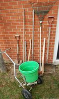 Group shot of all garden tools and spreader against brick wall