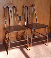 Front view of both wooden chairs showing spindle backs and seats