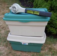 Stacked Rubbermaid totes with leaf blower resting on top