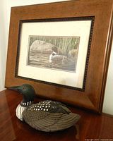 Loon figure in front of framed loon print