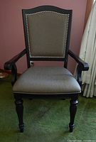 Front view of upholstered dining armchair showing frame, upholstery, nailhead trim