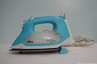Left side view of turquoise Oliso TG1600Pro iron showing body, handle, cord