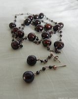 Necklace coiled with earrings showing dark pearls and silver chain