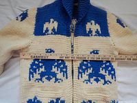 Full front view of cream and blue wool sweater coat with ruler for scale