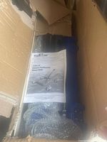 Photo showing the vehicle positioning wheel dolly partially wrapped in bubble wrap inside its box, with the user manual placed on top.