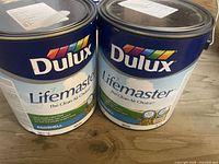Two 1-gallon cans of Dulux Lifemaster interior paint with visible brand and product info on the front labels.