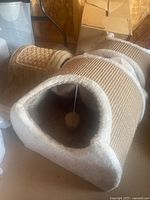 Photo shows a cat scratcher and tunnel with sisal rope scratching areas and a soft fabric tunnel entrance with a hanging ball toy inside.