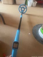 Blue and black children's metal detector showing the full length from coil end to control box with screen.