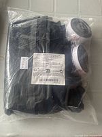 Sealed packaging containing folded black mesh screen and attached white and black rollers with instruction label visible on front.